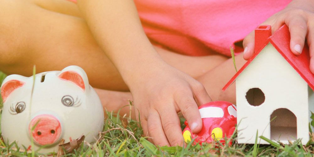 Una bambina gioca con una casa giocattolo: nelle vere abitazioni possiamo conservare l’energia con i giusti consigli