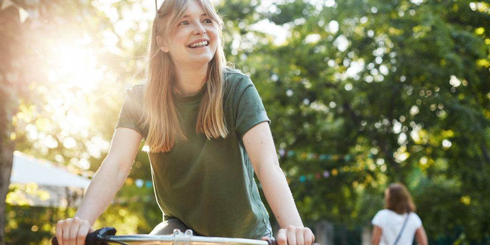 In un parco una ragazza sorride su una bici, un mezzo per il turismo sostenibile