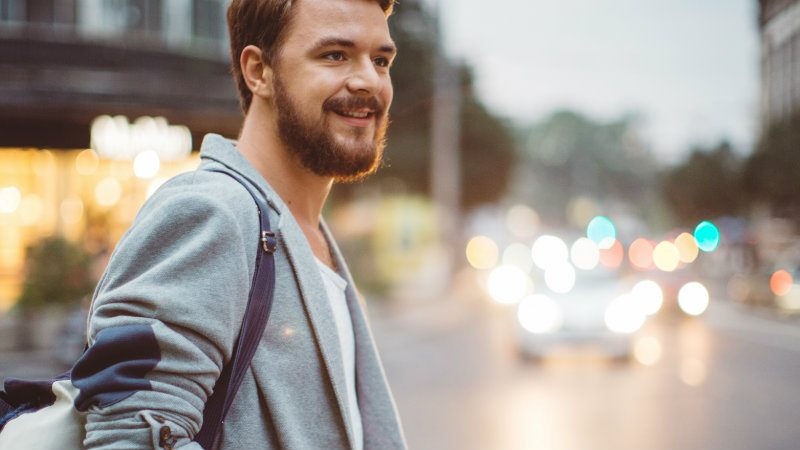 Un turista sorride in un paesaggio urbano: anche il turismo è sempre più sostenibile e green