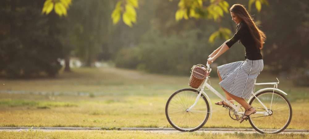 Una ragazza in bici in un parco: anche in Italia la rete di piste ciclabili è cresciuta per un turismo sostenibile