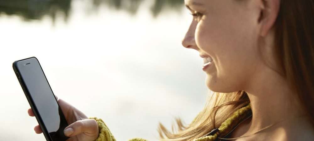 Una ragazza controlla lo smartphone, uno strumento per evitare sprechi di energia e risparmiare