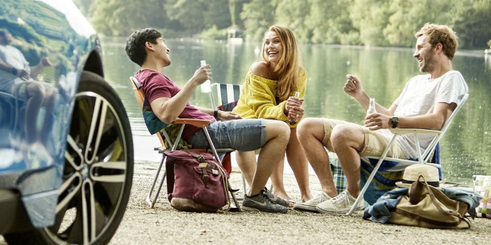 Una ragazza e due ragazzi seduti su sedie portatili accanto a un lago: anche il turismo sostenibile è uno strumento per un futuro migliore
