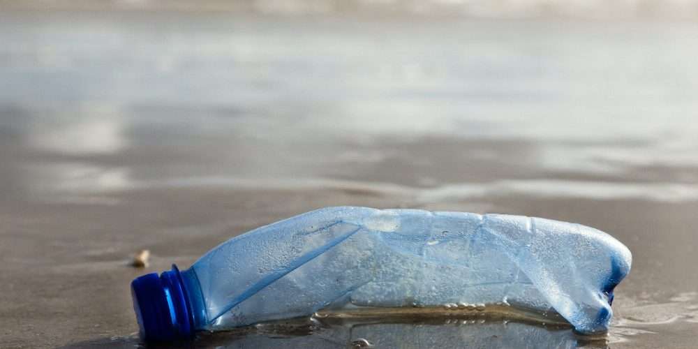 Una bottiglia di plastica su una spiaggia: un aspetto dell’inquinamento delle coste