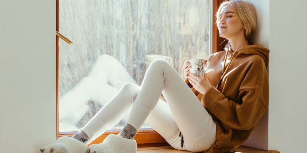 Una ragazza si gode il tepore domestico: per il buon funzionamento della caldaia è importante la revisione con rilascio di bollino blu