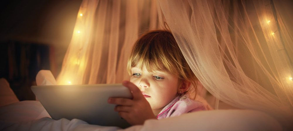 Una bambina legge sul tablet: anche i più piccoli possono imparare a risparmiare energia con i giusti consigli