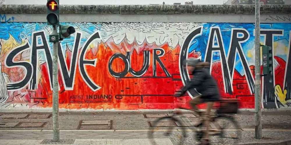 Un uomo in bicicletta passa davanti a un murales colorato
