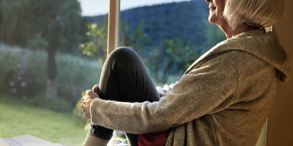 Una donna si gode il sole di una giornata invernale in una casa ben isolata termicamernte