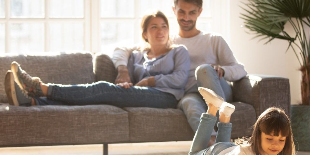 Una giovane coppia con la figlia si rilassa in un soggiorno riscaldato con una caldaia a condensazione