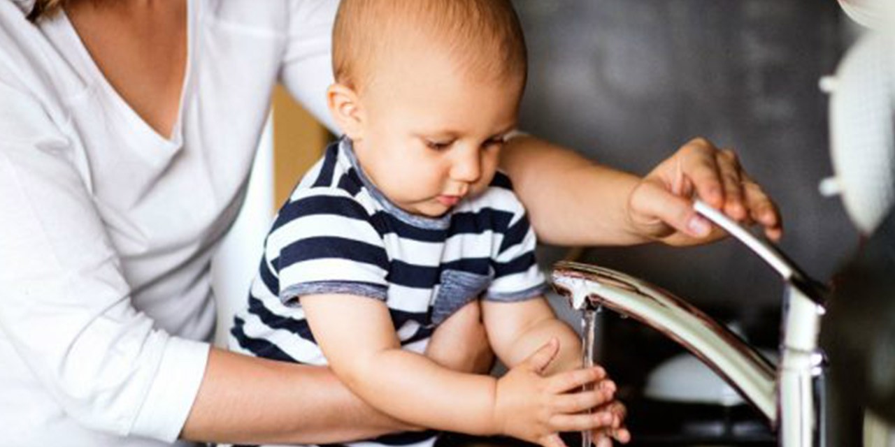 Un bambino aiutato dalla madre a lavarsi le mani: esistono molti suggerimenti per ridurre lo spreco di acqua