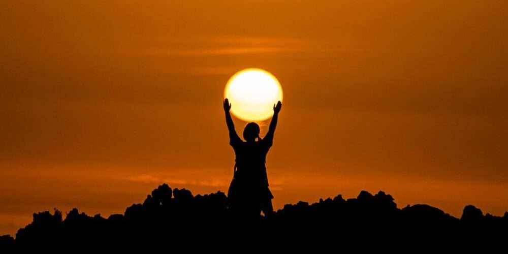 Un uomo dinanzi a un tramonto: l’energia del sole è fondamentale per il nostro corpo e per l’ambiente