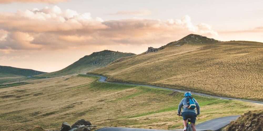 Una ragazza in bici attraversa la campagna: il cicloturismo è una tendenza delle ultime estati