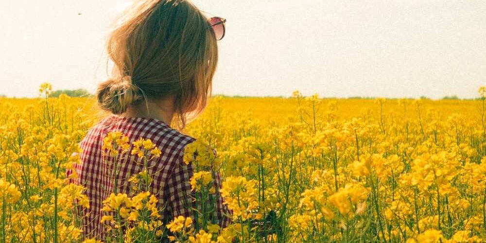 Una ragazza di spalle in un campo fiorito per la Giornata Mondiale dell’Ambiente