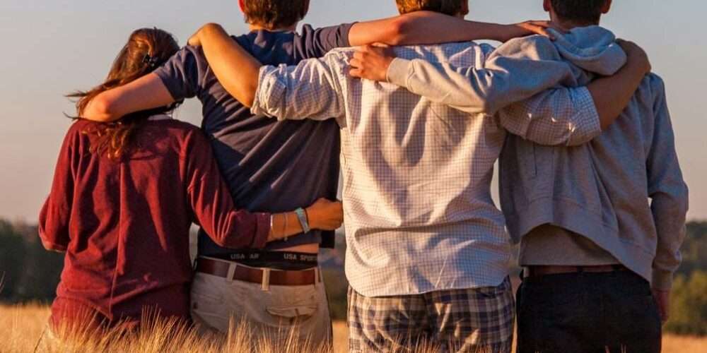 Un gruppo di ragazzi abbracciati in un campo: vivere la natura significa promuovere uno stile di vita sostenibile