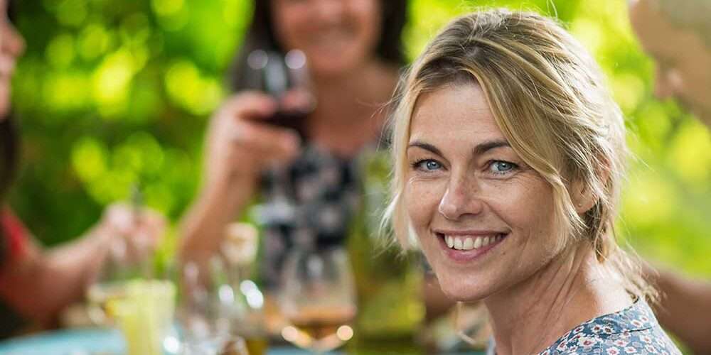 Una ragazza sorride durante un pranzo: serenità e benessere delle persone sono legate alla sostenibilità delle aziende