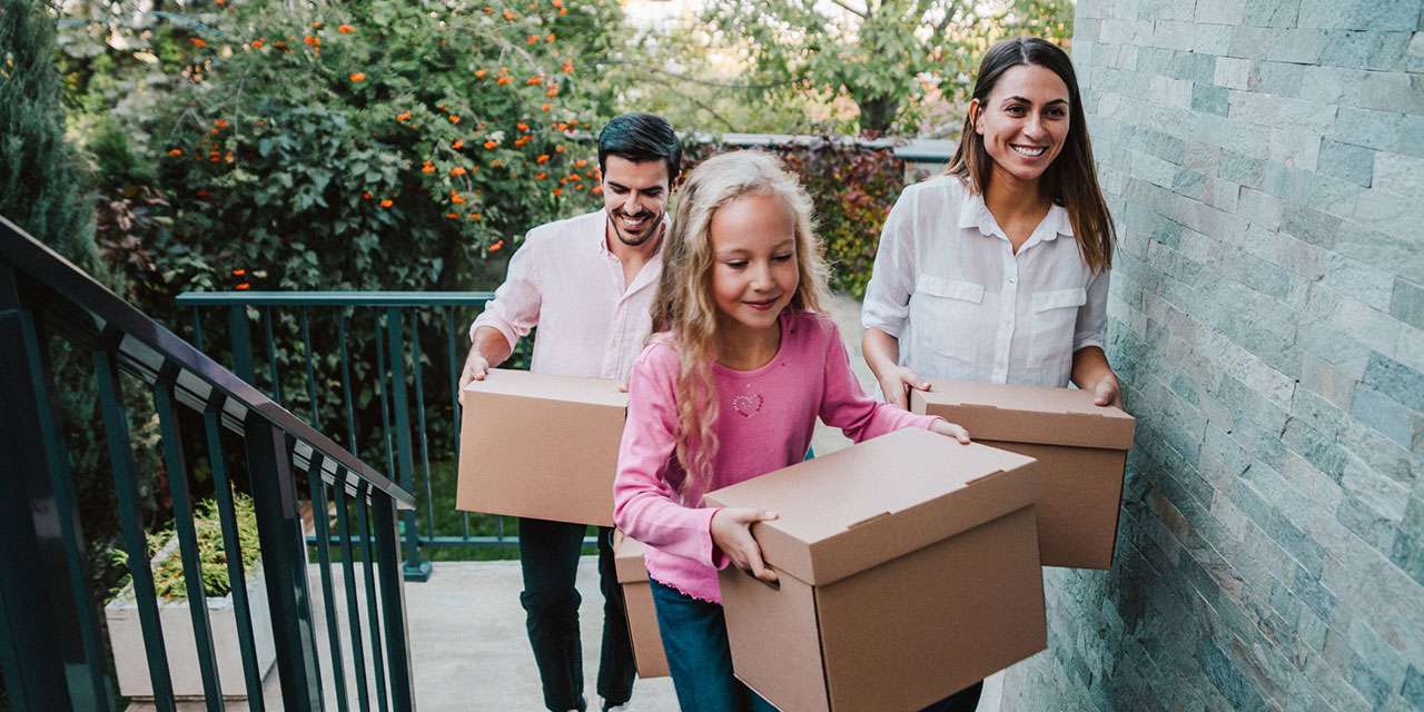 Un papà, una mamma e una bambina trasportano delle scatole durante un trasloco