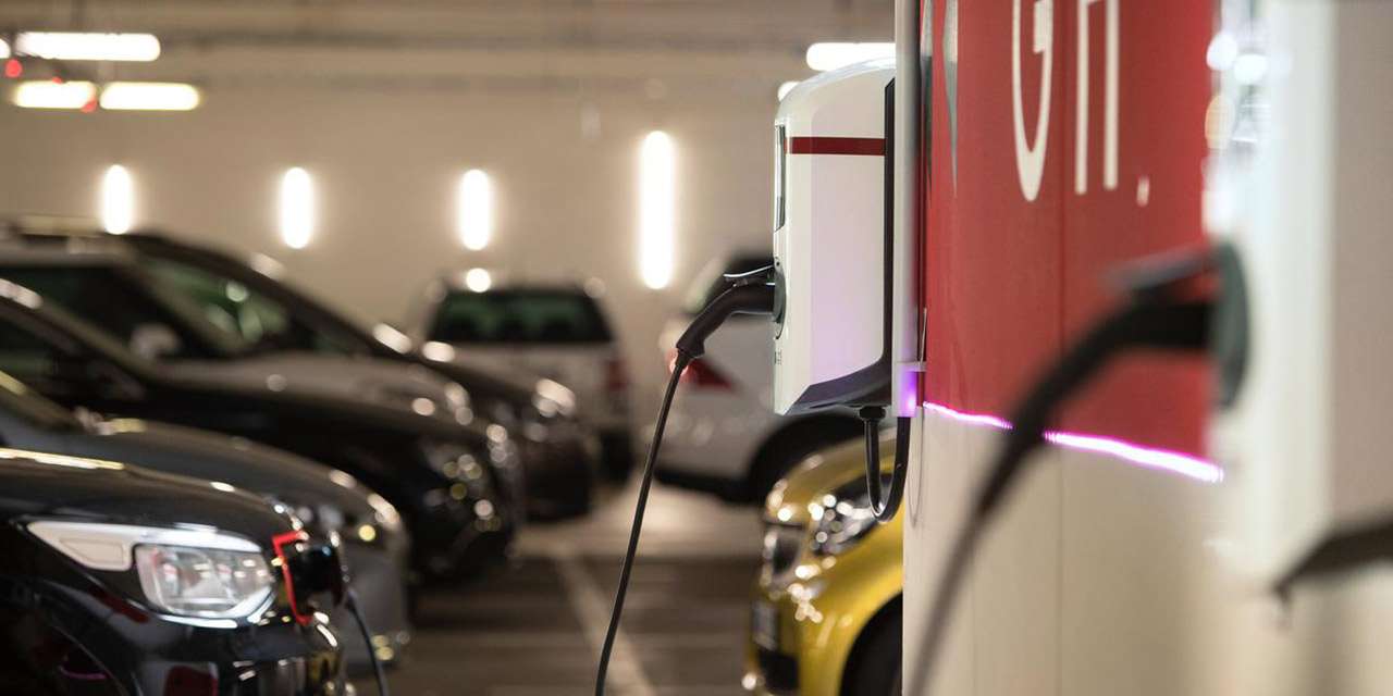 Garage di un condominio con colonnine e auto elettriche in ricarica
