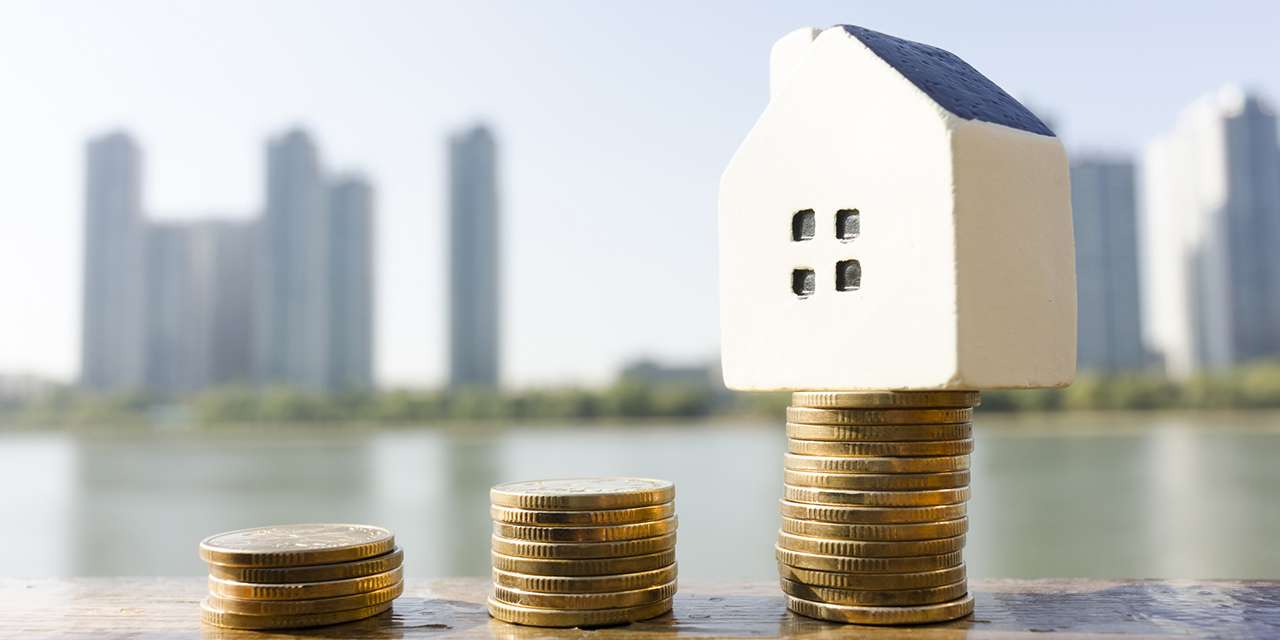 Una piccola casa accanto a monete: l’economia domestica dipende anche dai prezzi dell’energia