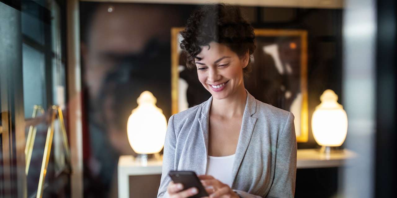 Una ragazza sorride mentre usa lo smartphone: il feedback dei clienti migliora l’App E.ON