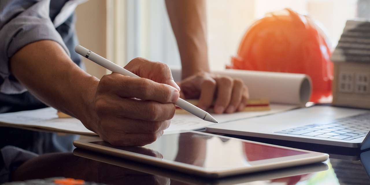 Un tecnico con laptop e tablet controlla i dati della diagnosi energetica di un condominio