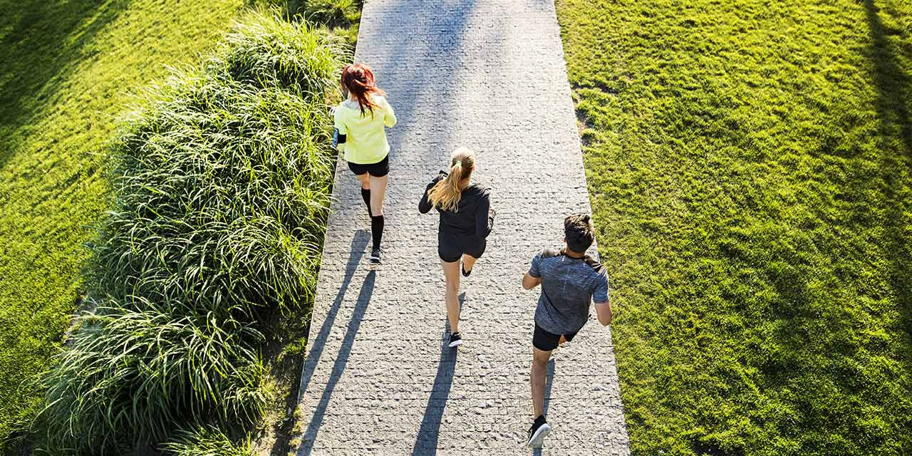 Due ragazze e un ragazzo corrono in un parco cittadino, uno degli ambienti centrali nei progetti urbani del futuro