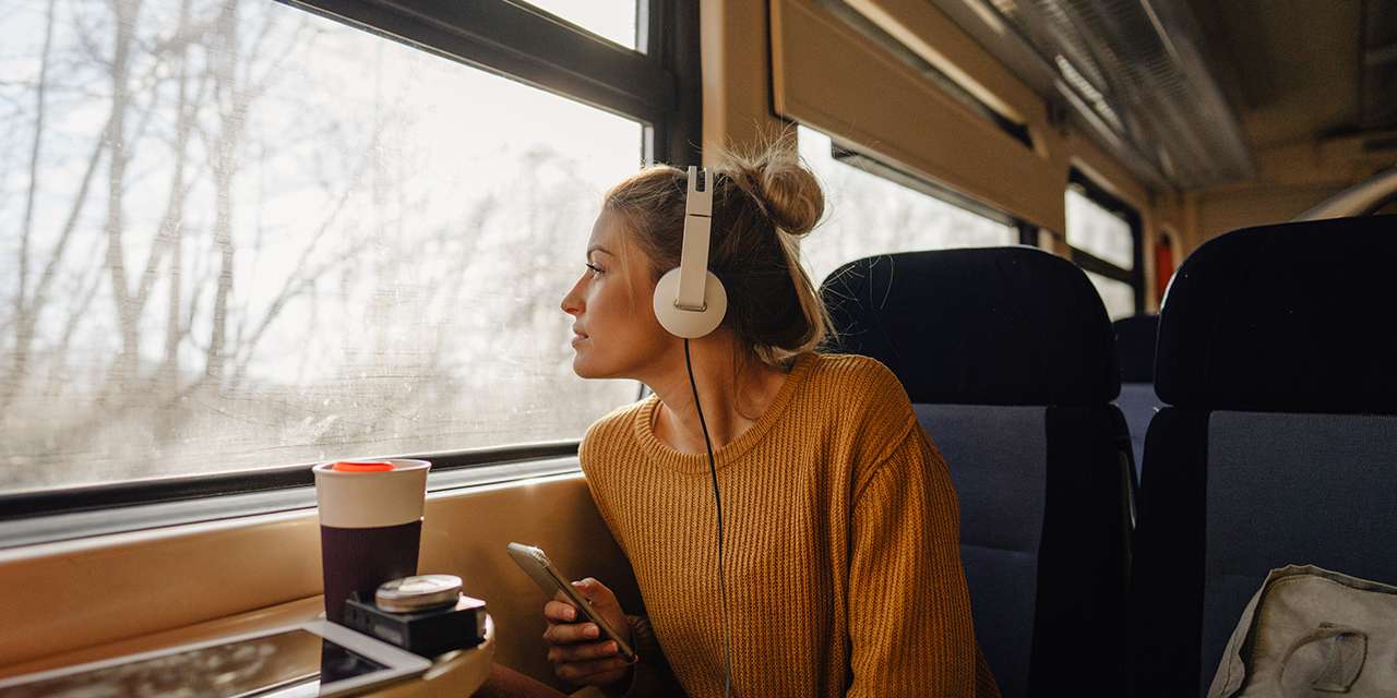 Una ragazza ascolta musica in treno, un mezzo sostenibile per un turismo responsabile