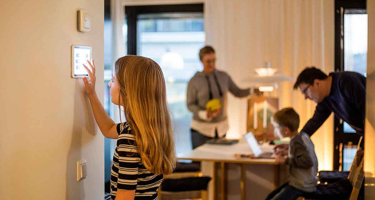 Una ragazza imposta un display a muro per regolare l’illuminazione domestica, comportamento consapevole per risparmiare 