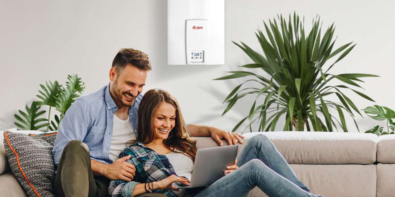 Una coppia controlla il computer su un divano, in un soggiorno riscaldato da una caldaia a condensazione