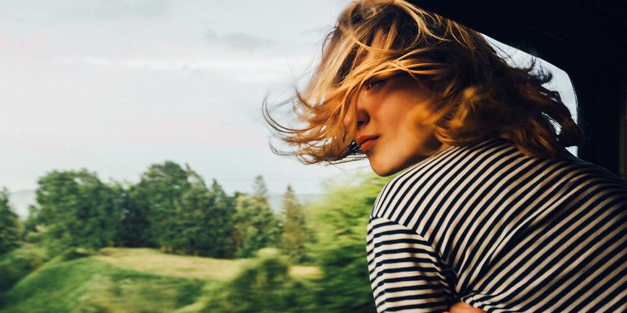 Una ragazza affacciata a un finestrino durante un viaggio: anche i mezzi di trasporto impattano sull’inquinamento