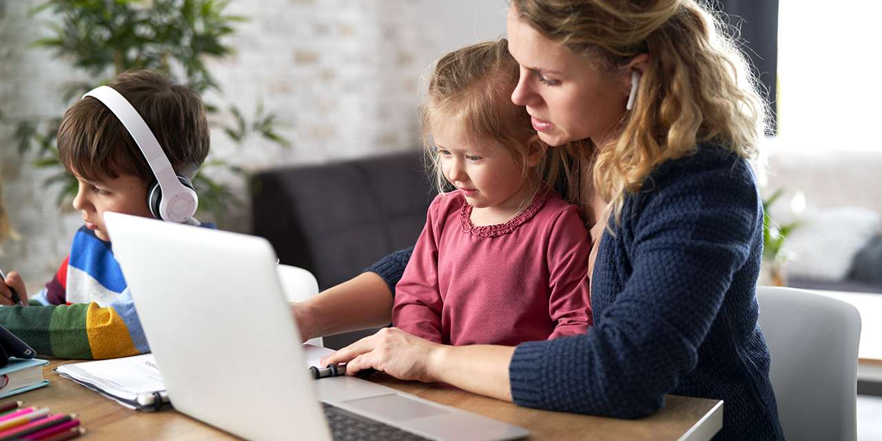 Un bambino e una bambina sono aiutati dalla mamma nella didattica a distanza