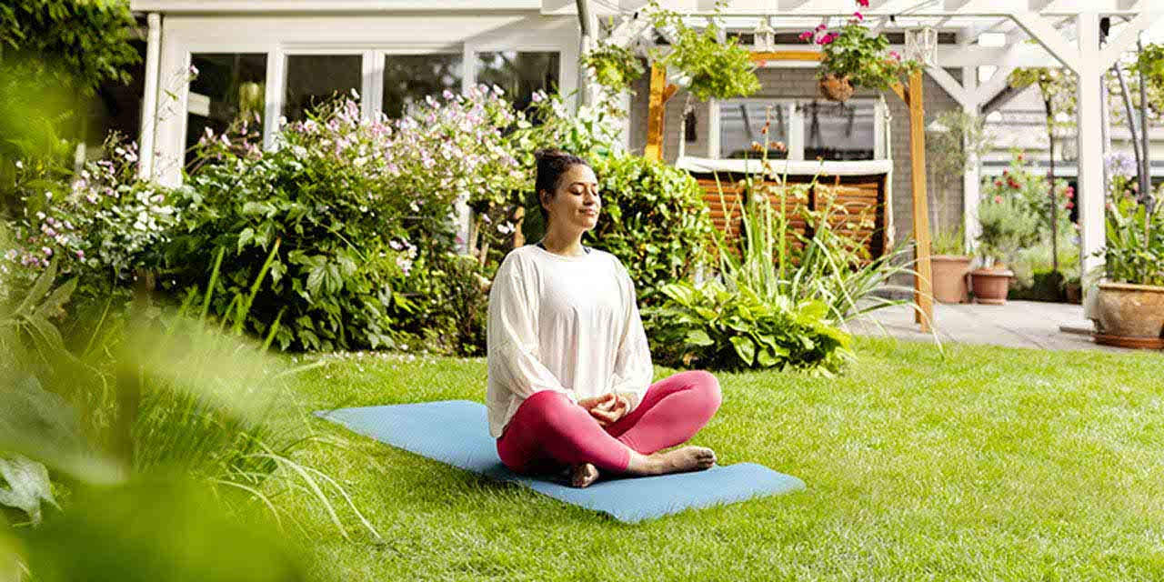Una ragazza fa yoga su un prato in un giardino di una casa alimentata dal fotovoltaico