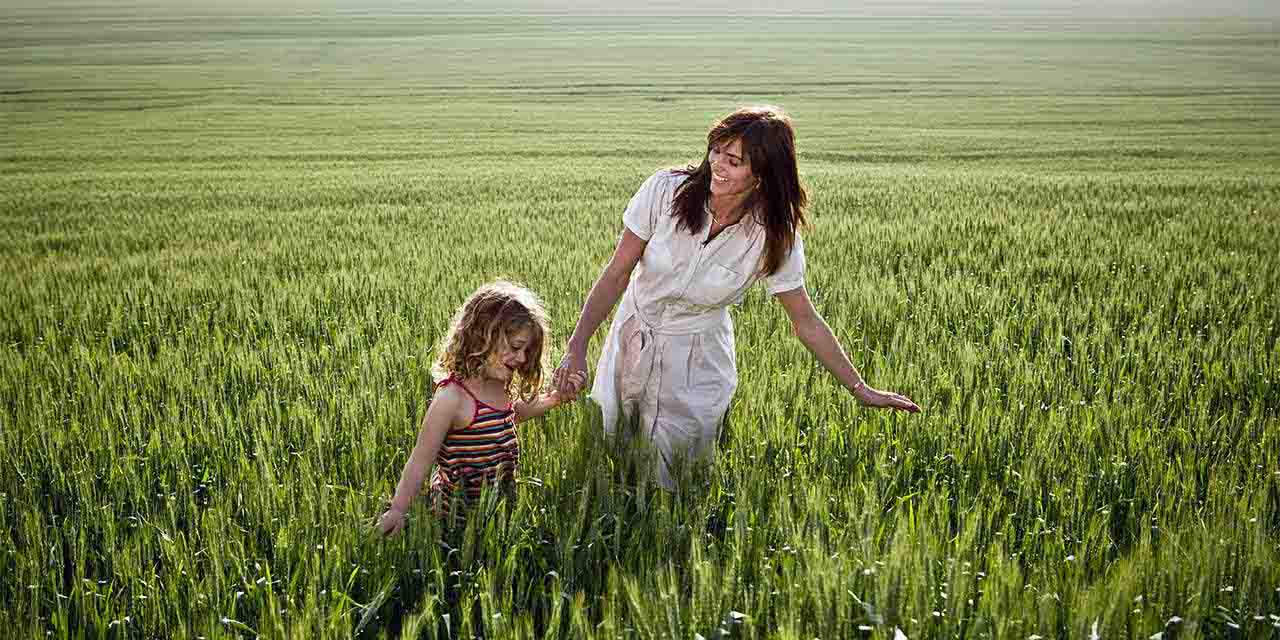 Una mamma e una bambina in un grande campo di grano: l’impatto dell’uomo sul Pianeta ha effetti sui cambiamenti climatici