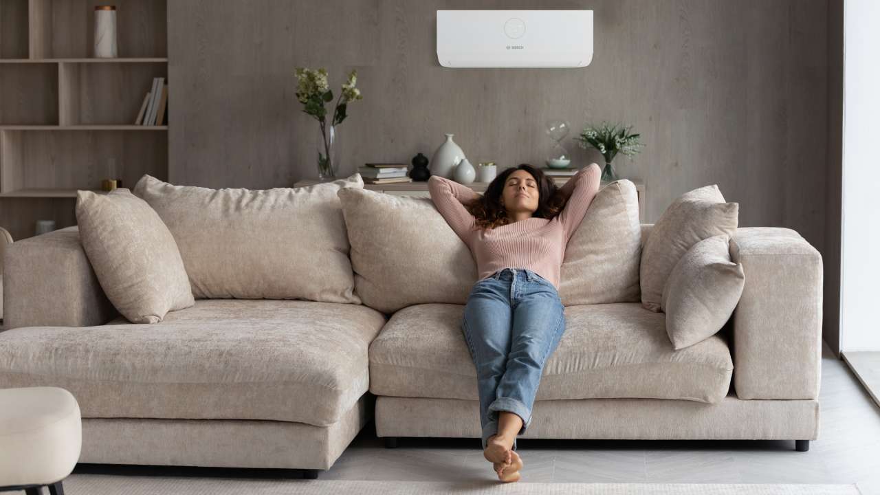 Una ragazza rilassata sul divano in un soggiorno con un condizionatore a risparmio energetico