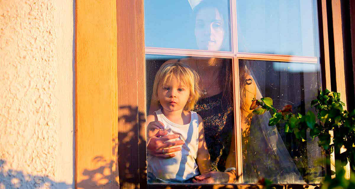 Una mamma con bambino affacciati a una finestra di un edificio con cappotto termico per la transizione energetica