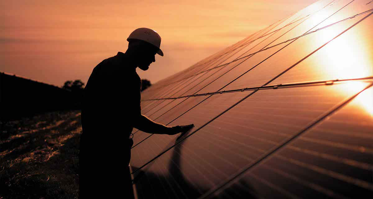 Un tecnico controlla pannelli fotovoltaici, strumenti fondamentali per l’indipendenza energetica