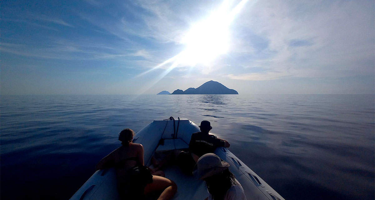 La prua di una imbarcazione procede verso un’isola: il volontariato ambientale rende più belle le vacanze estive al mare