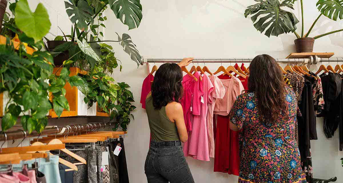 Due giovani clienti, di spalle, cercano un capo d’abbigliamento tra quelli appesi alle stampelle