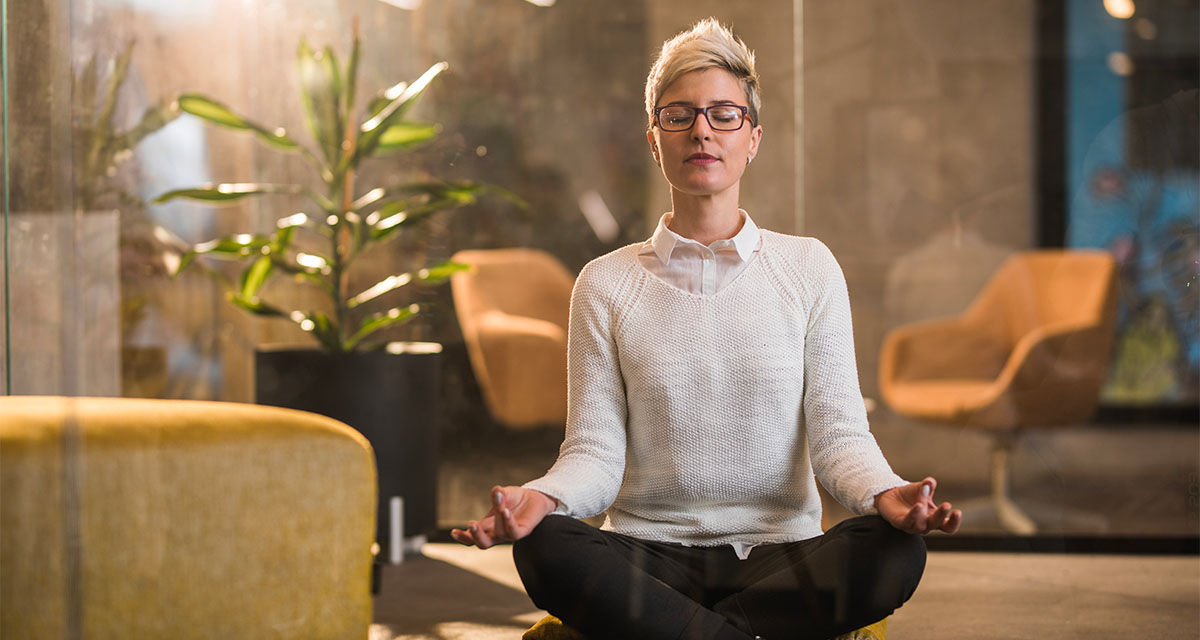 Una ragazza medita a gambe incrociate in uno studio, seduta sul pavimento