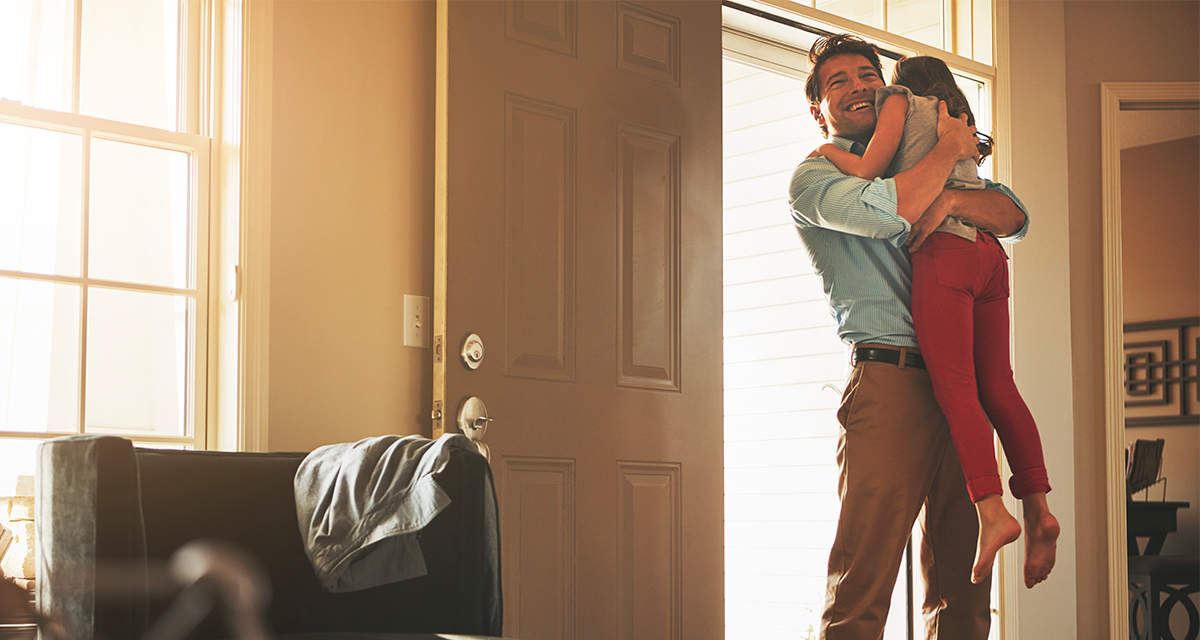 Un papà abbraccia la figlia in un soggiorno luminoso