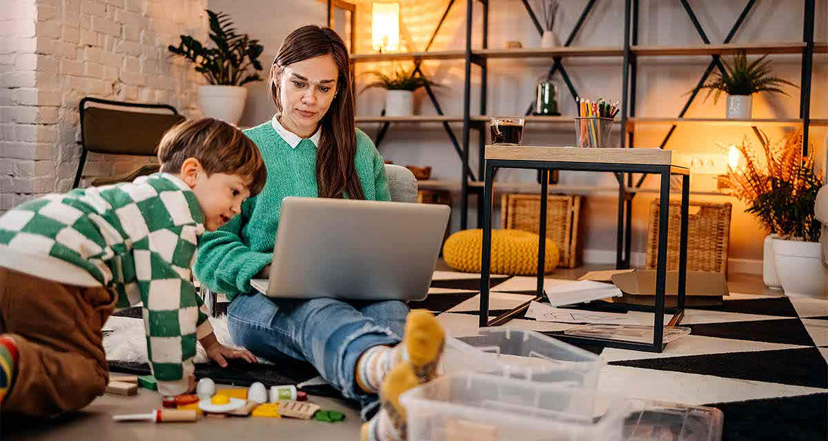 Una ragazza scrive su un portatile, con un bambino accanto, in un soggiorno riscaldato da una pompa di calore ibrida