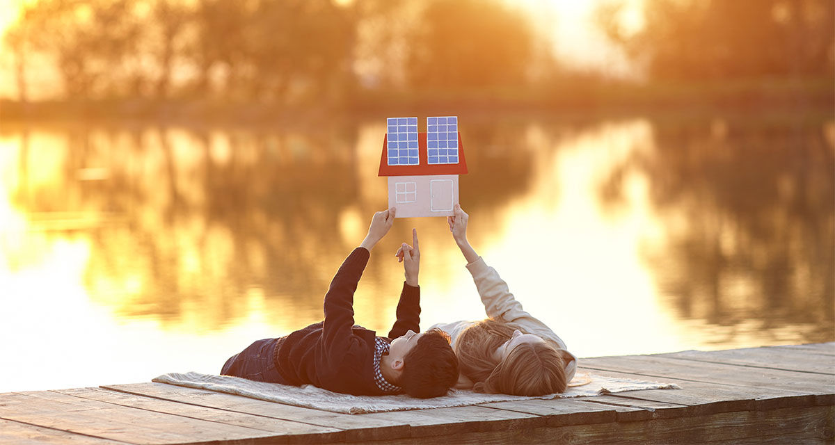 Due ragazzi distesi davanti a un lago sognano una casa green