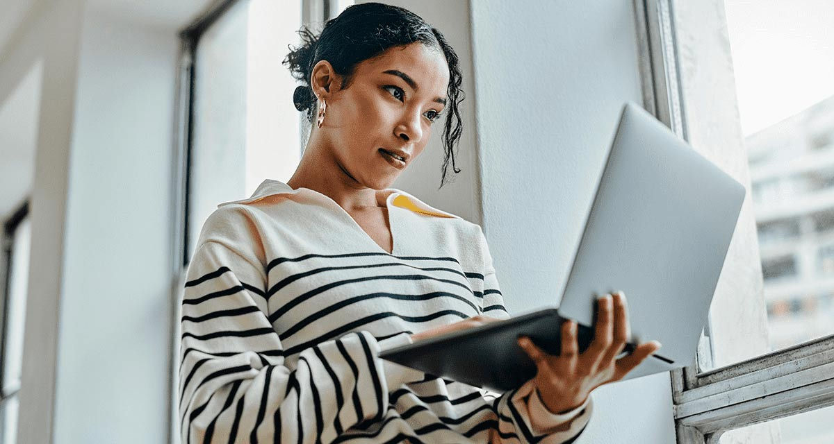 Una ragazza in piedi consulta attentamente lo schermo di un laptop