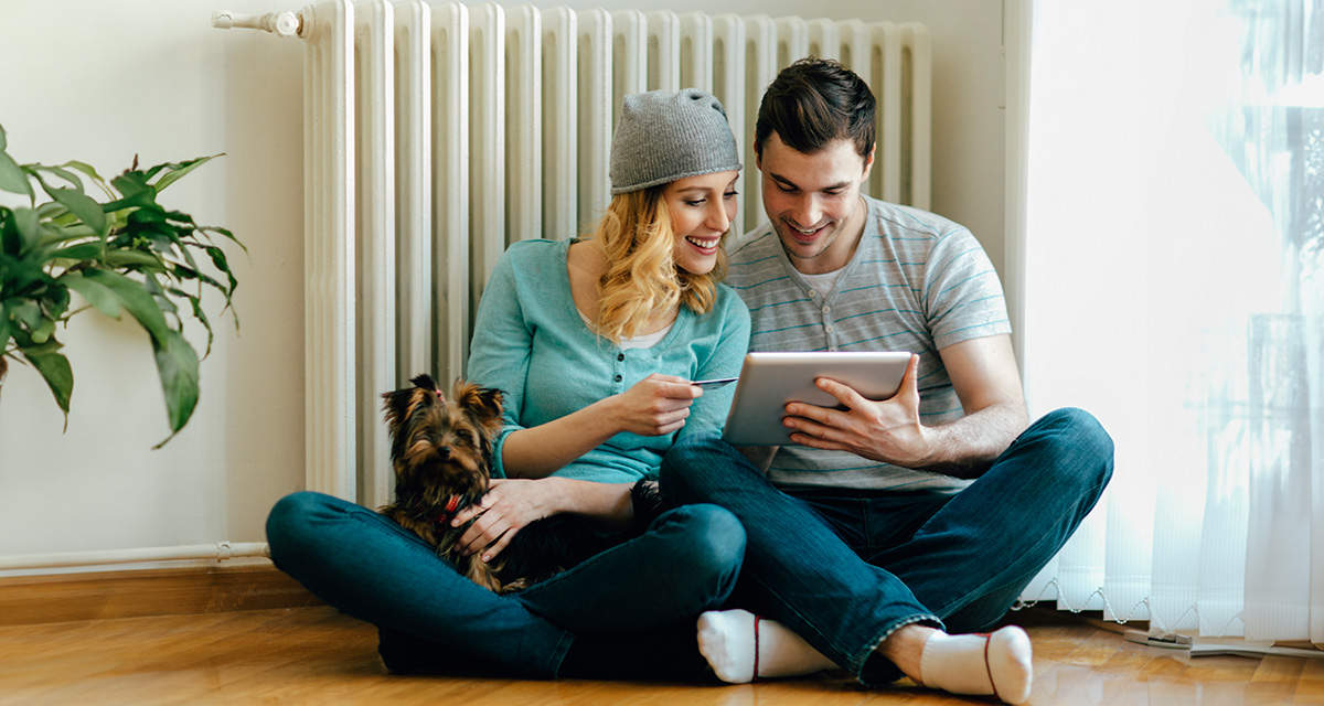 Una giovane coppia, seduta sul pavimento, controlla il tablet