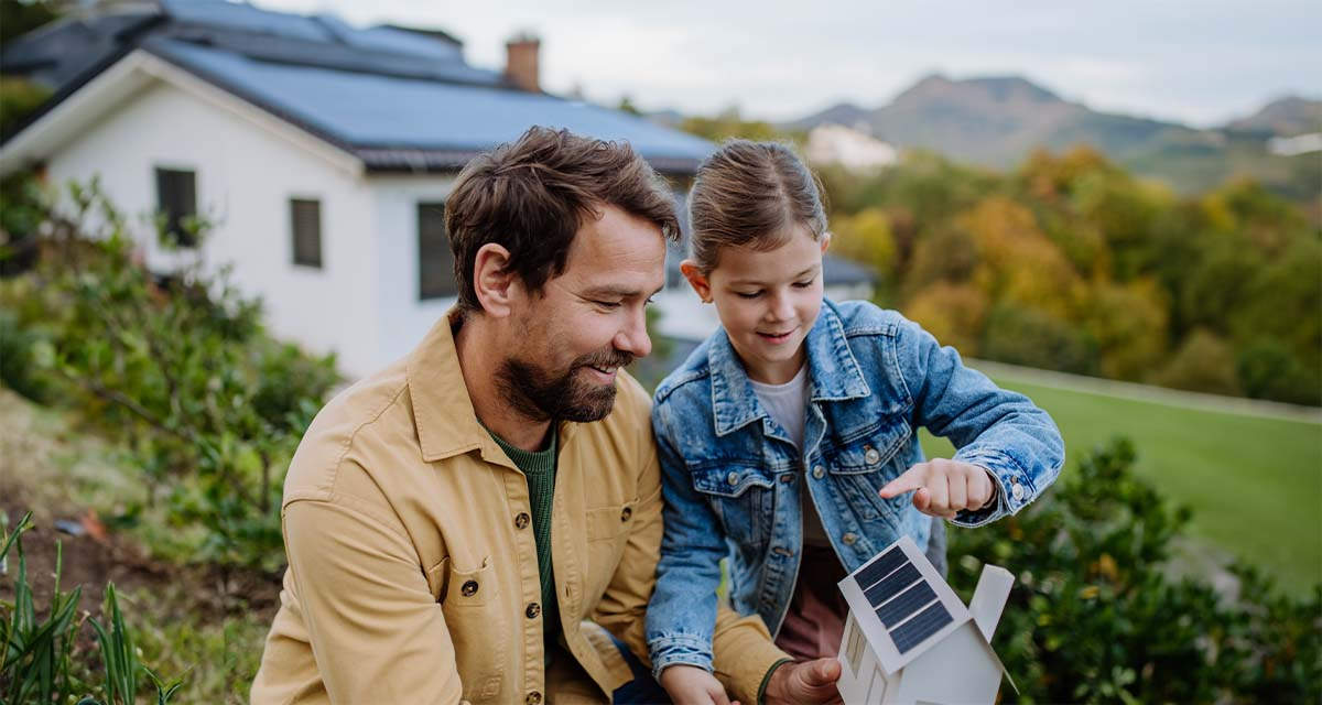 Un papà gioca con la figlia con un modellino di impianto solare: il fotovoltaico cresce grazie ad accessibilità e convenienza