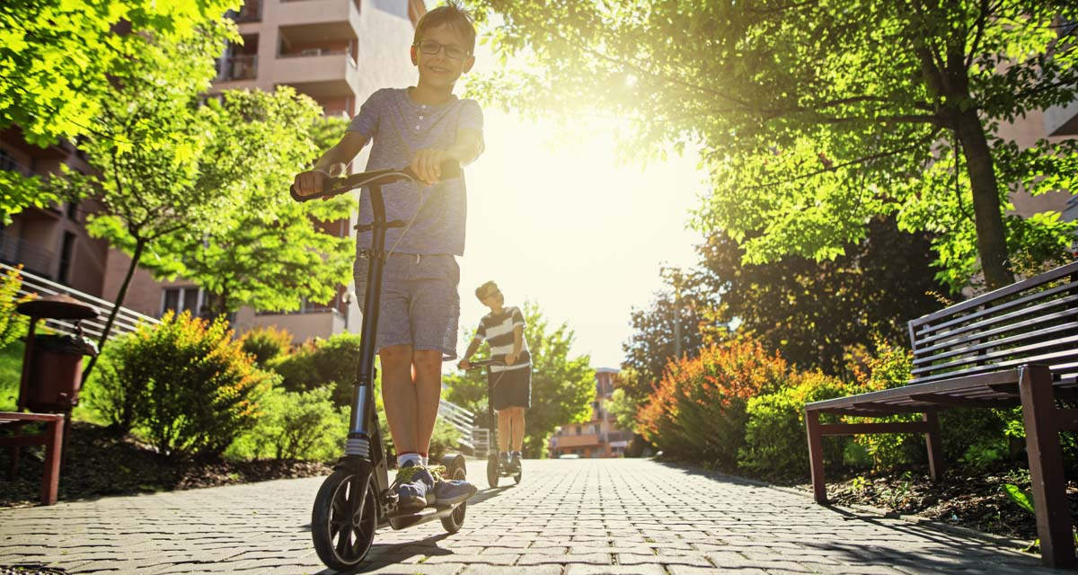 Ragazzi in monopattino in un viale di un parco in un ecoquartiere