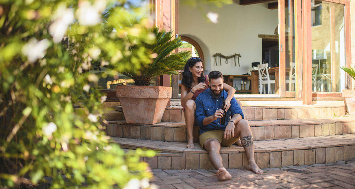 Una coppia si rilassa seduta sulle scale all’ingresso della casa delle vacanze