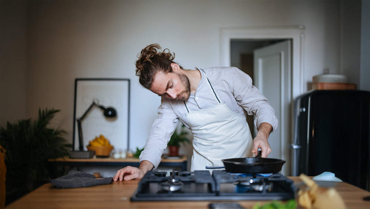 Un giovane cuoco alle prese con i fornelli: la cucina è uno degli usi del gas naturale