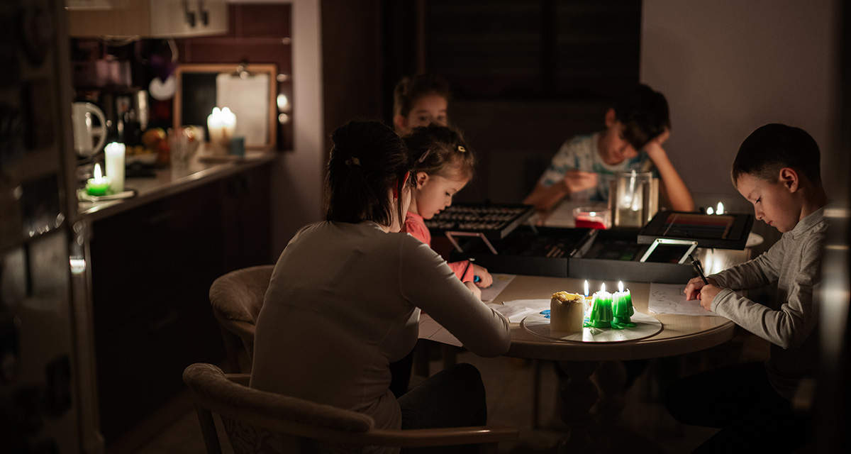 Dei bambini giocano intorno a un tavolo con candele accese: per i blackout imprevisti ci sono rimborsi in bolletta