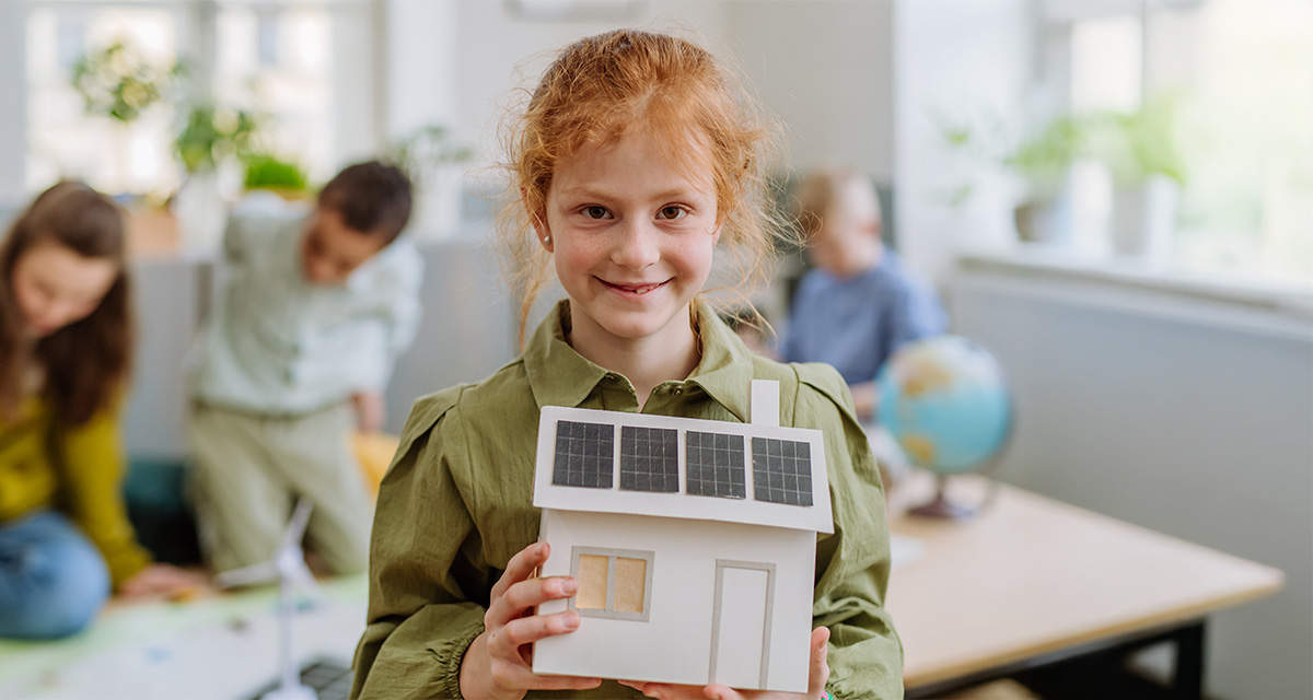 Una bambina mostra un modellino di casa con pannelli fotovoltaici: l’edilizia è un settore cruciale per la transizione energetica, digitale e sociale