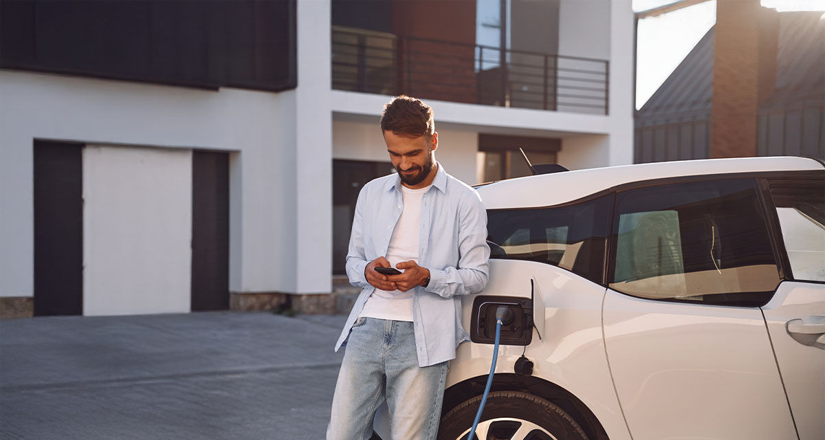 Un ragazzo ricarica l’auto elettrica in una stazione pubblica