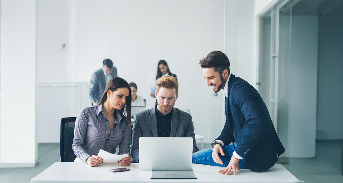 Tre colleghi al lavoro intorno a un computer: l’innovazione responsabile è la chiave per un impatto positivo delle aziende sul futuro